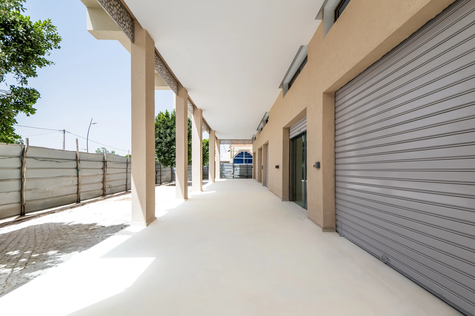 Arcades du rez-de-chaussée ouvertes sur la rue, avec leurs rideaux métalliques