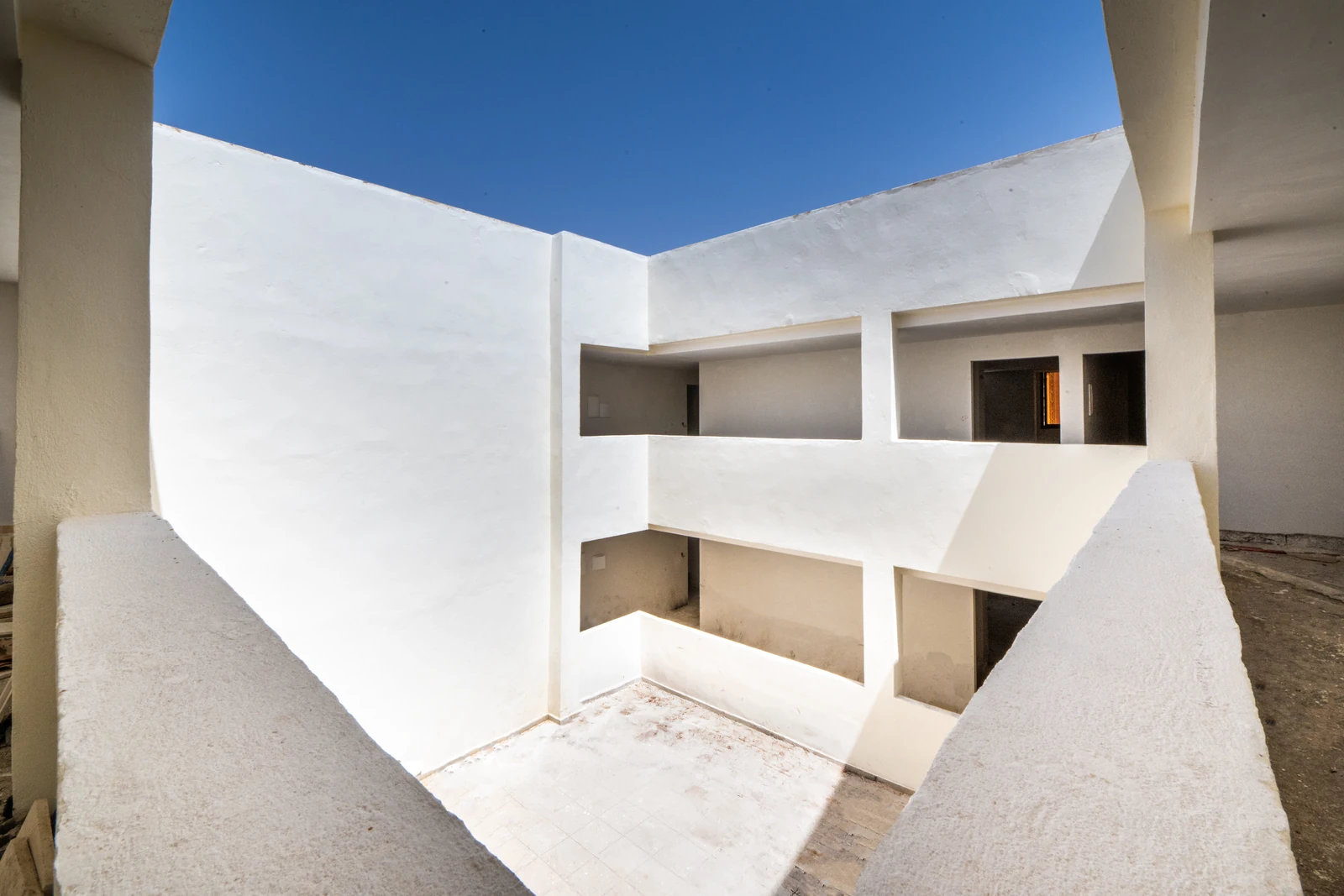 Patio intérieur aux murs blancs, ouvert sur le ciel, desservant les niveaux